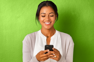 Photo of woman holding phone in front of a green wall